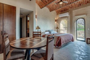 A room with a dining table, chairs, a bed with a view through an arched window, and a brick ceiling. - Villa Tortuga- Private Lake-View Hacienda Estate in West Ajijic with Pool Cabana (San Antonio Tlayacapan)