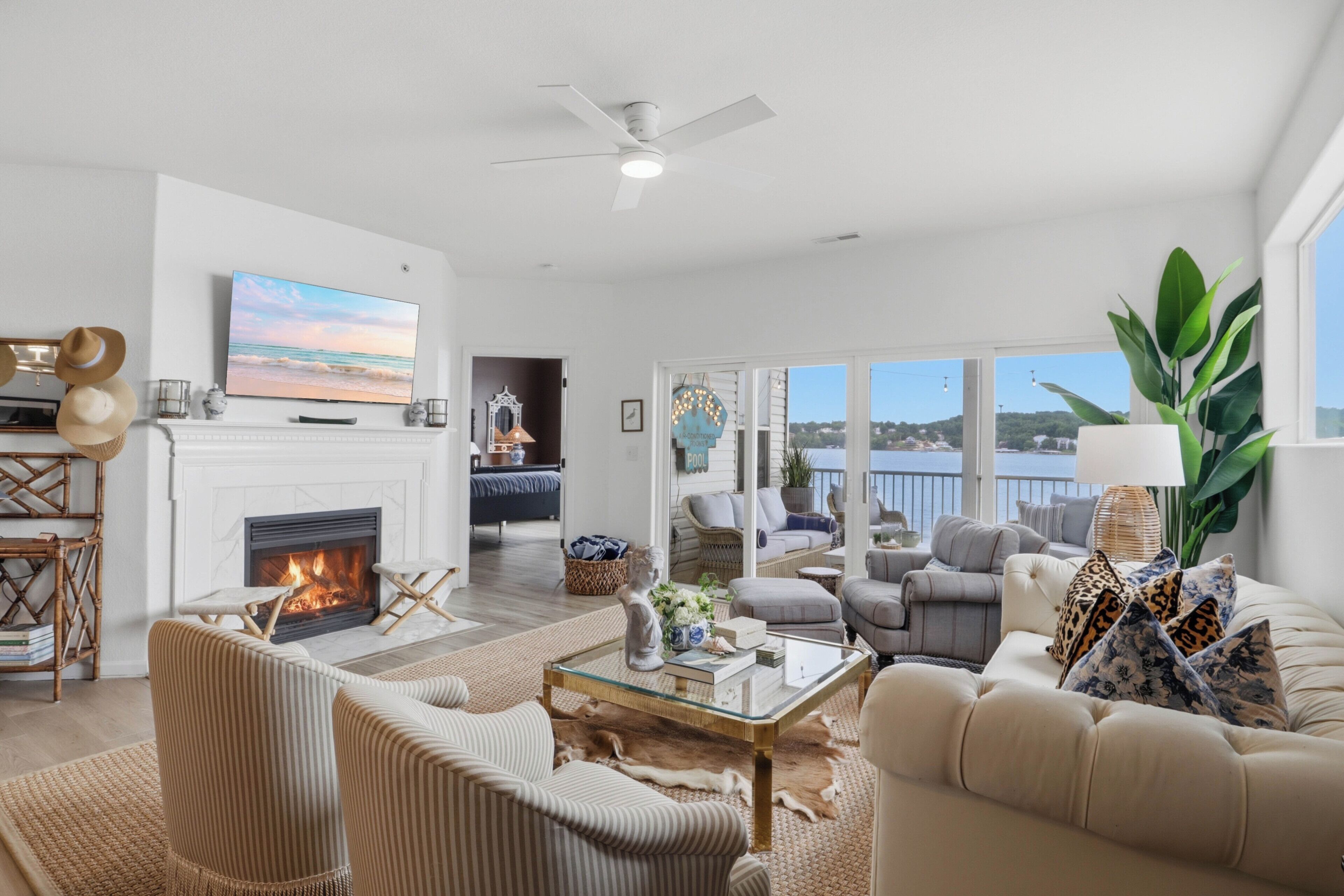 A spacious living room with a fireplace, comfortable seating, a television, and a view of the outdoors.