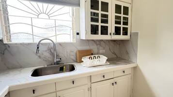 A kitchen with a sink, cabinets, and a window with blinds.