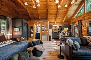 A cozy log cabin interior with a living room, dining area, and kitchen. - Studio cabin in the Smokies. Sauna, hot tub, fire pit, private deck, EV charger (Sevierville)