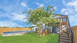 A backyard with a swimming pool, a wooden deck, and a tree. - Holds 8 · Pool · 3BR/2BA Lower-Unit Duplex Peacock Horse Beach NearbyOut of City (Galveston)