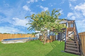 A backyard with a swimming pool, a wooden deck, and a tree. - Holds 8 · Pool · 3BR/2BA Lower-Unit Duplex Peacock Horse Beach NearbyOut of City (Galveston)