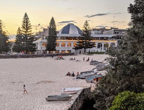 Ein Strand mit Booten, ein großes Gebäude mit einer Kuppel und Personen.