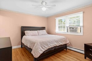 A bedroom with a bed, a ceiling fan, a window with blinds, and an air conditioning unit. - Charming Hampton Bays Home Near Beaches (Hampton Bays)