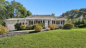 A single-story house with a front porch, a garage, and a well-maintained lawn. - Charming Hampton Bays Home Near Beaches (Hampton Bays)