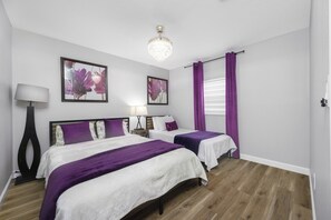A bedroom with two beds, a chandelier, and artwork on the wall. - Main house and guest house, Events, Heated Pool 15min to Clw Beach (Clearwater)