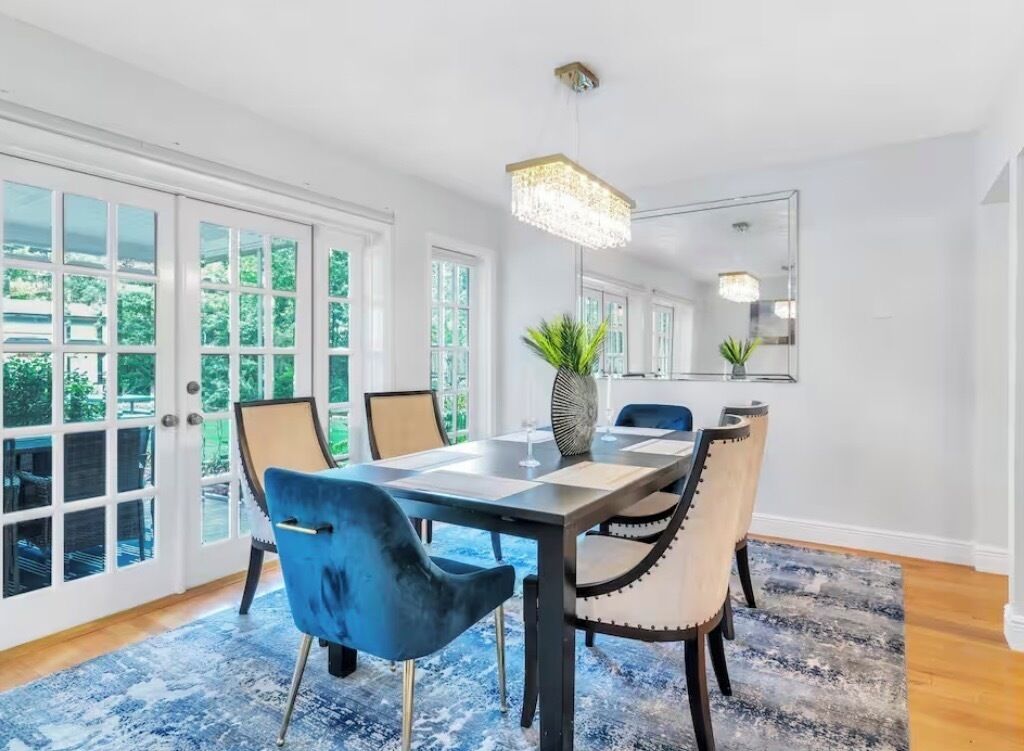 A dining area with a rectangular table, blue chairs, and a chandelier.