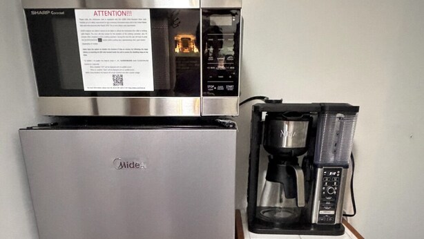 Una kitchenette compacta con refrigerador, microondas y cafetera.