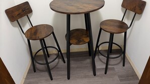 Un pequeño comedor con una mesa redonda y tres sillas.