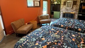 Un dormitorio con dos camas, una silla, una mesita y una chimenea.