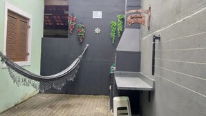 A hammock hanging between two buildings, a small table, and a sign on the wall. - Feet in the Sand / Beach House / Bertioga (Bertioga)