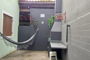 Uma rede esticada entre dois edifícios, uma mesa pequena e uma placa na parede.