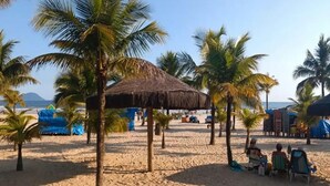 A sandy beach with palm trees and a thatched-roof structure. - Feet in the Sand / Beach House / Bertioga (Bertioga)