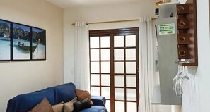 A room with a blue sofa, a door with a grid pattern, a wall-mounted electrical panel, and a framed picture of a boat on water.