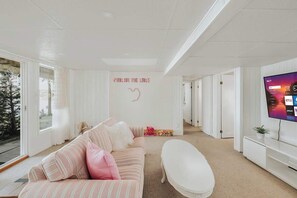 A modern living room with a large TV, a sofa, a coffee table, and a wall with a decorative sign.