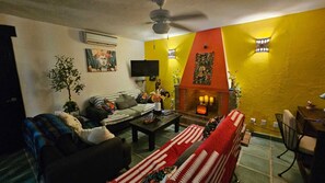 Ein Wohnzimmer mit einer Couch, einem Couchtisch, einem Kamin und einem Fernseher.