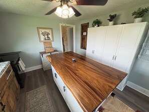 A kitchen with a wooden island, white cabinets, and a ceiling fan. - Cozy Country Cottage | 10 Min to Downtown Elkin (Elkin)