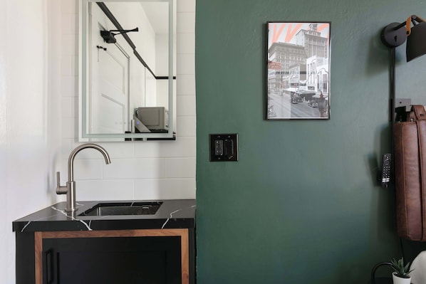 A modern bathroom with a black sink, a mirror, a green wall, and a framed picture. - La Ventana Hotel - Historic Hotel Stay in the Gaslamp Quarter (San Diego)