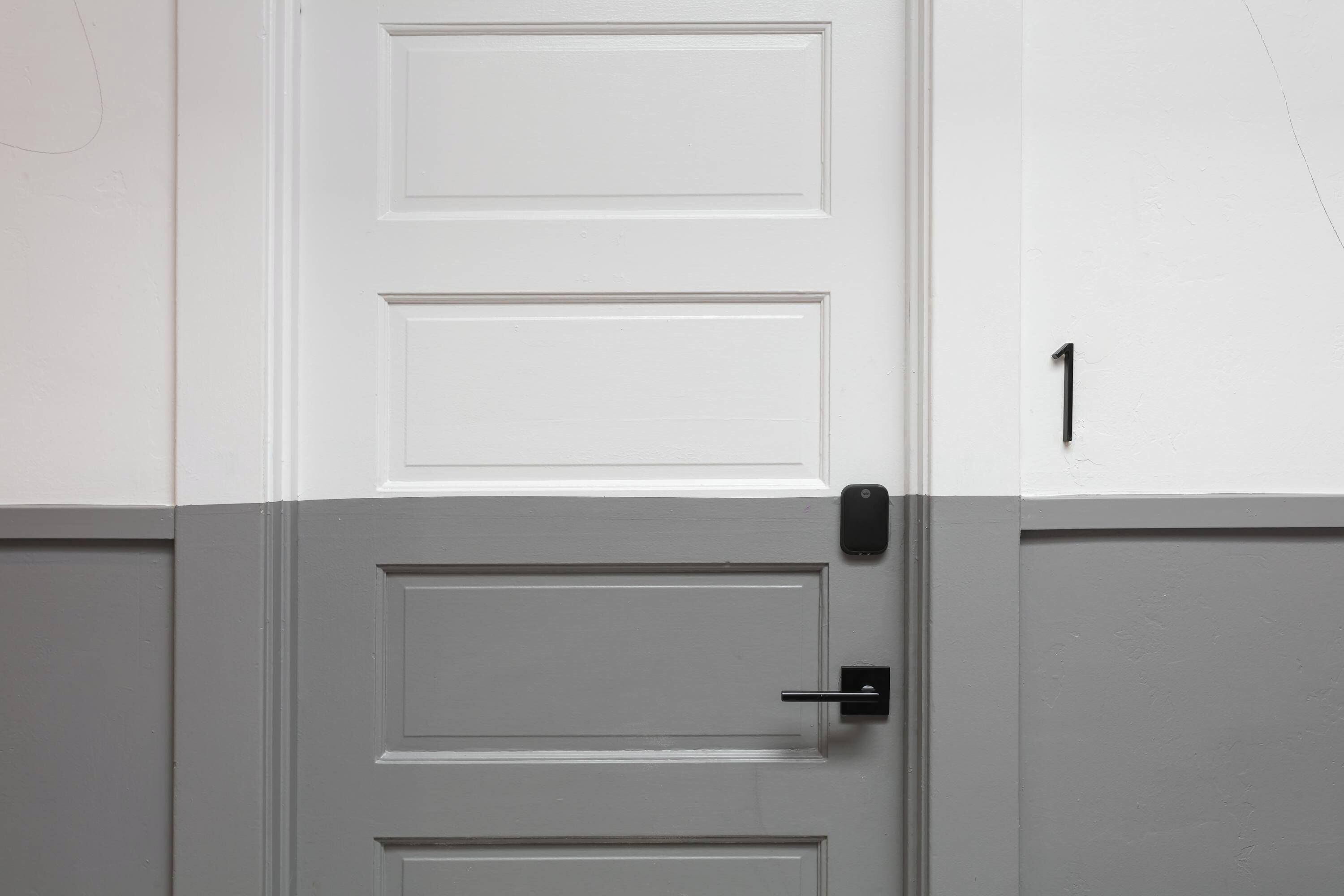 A white door with a black handle and a number '1' on the adjacent wall.