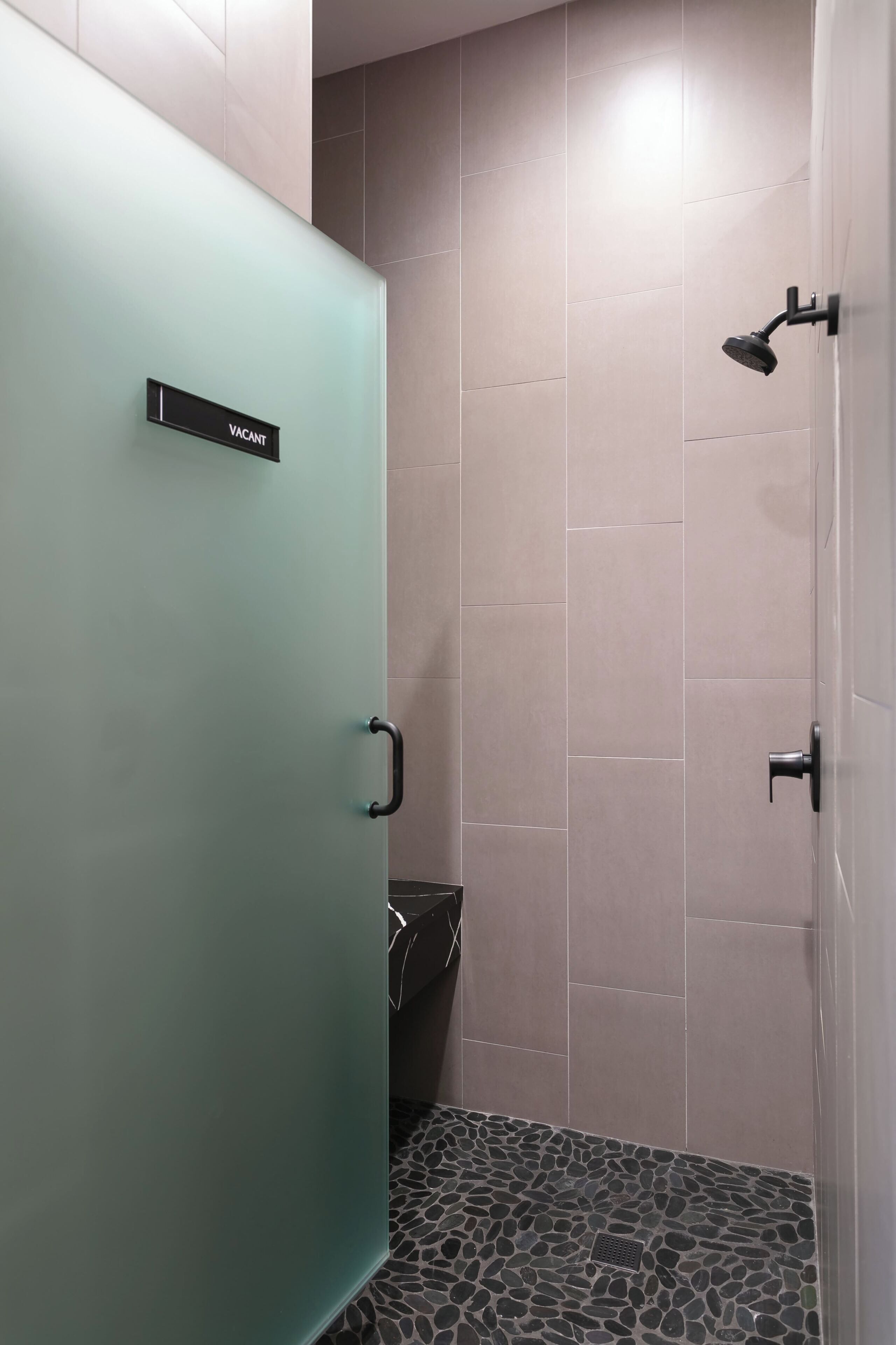 Une salle de bain avec une douche, des toilettes et une porte portant l’inscription « LIBRE ».