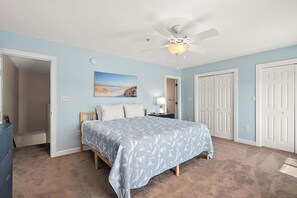 Ein Schlafzimmer mit Bett, Deckenventilator, Nachttisch und Tür.