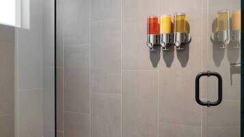 A modern bathroom with grey tiles, a glass shower enclosure, and a marble vanity.