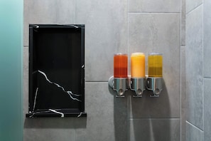 A wall-mounted beverage dispenser with three different colored drinks, a black-framed mirror, and a tiled wall. - La Ventana Hotel - 1BR Escape Queen Bed, WiFi & Kitchenette (San Diego)