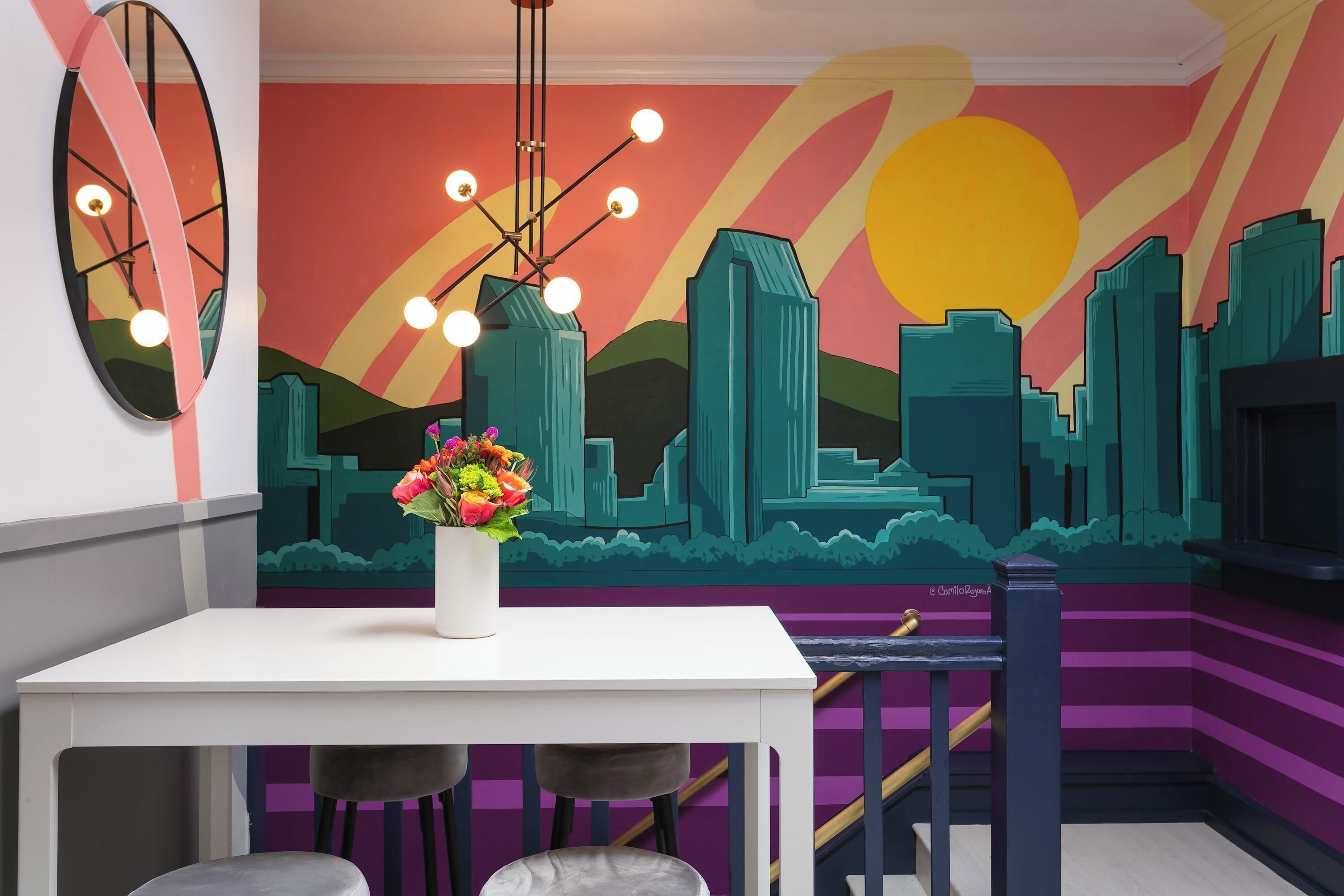 A modern interior with a cityscape mural, a white table, and bar stools.