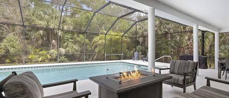Un patio exterior con piscina, asientos y una chimenea.