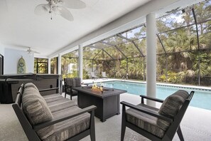 An outdoor seating area with a pool view, a fire pit table, and a hot tub. - Heated Pool Hot Tub Game Room Jupiter Farms Home (Jupiter)