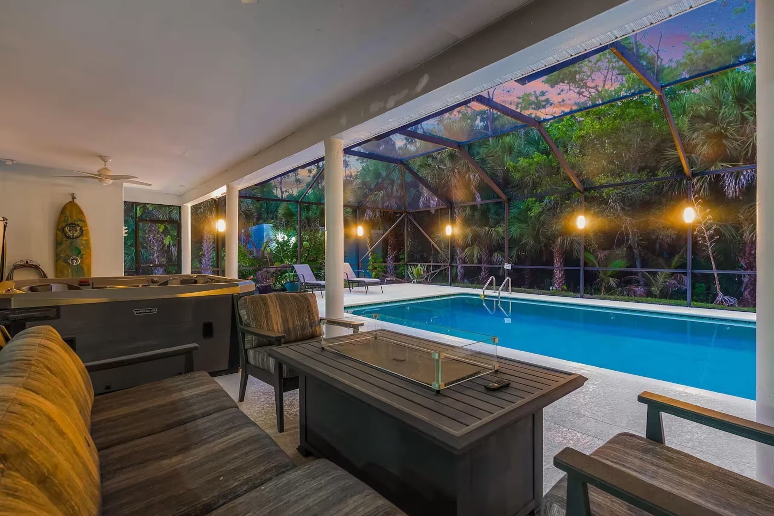 Un área de piscina interior con deck de madera, sillas de descanso y un bar.
