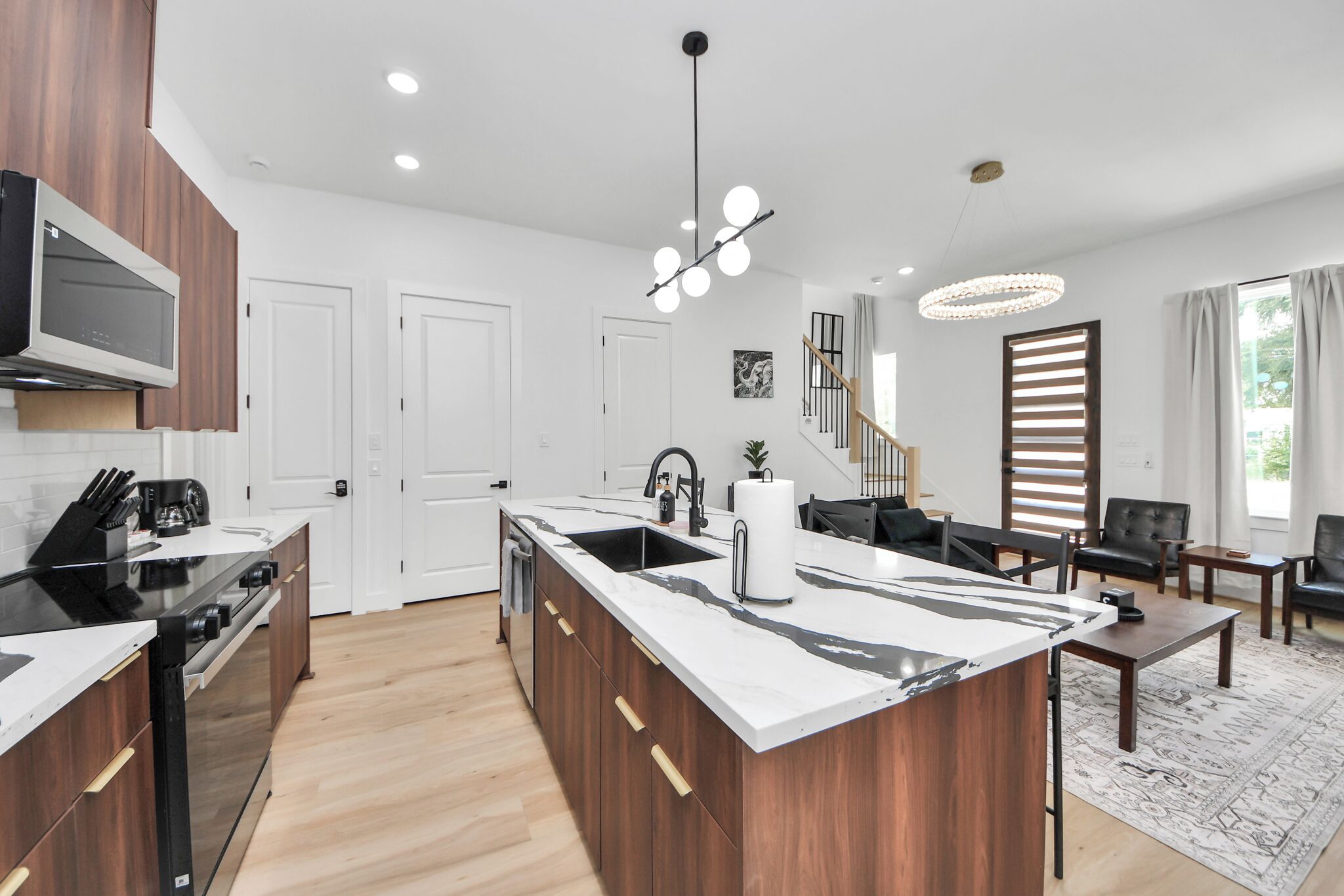 A modern kitchen with a central island, wooden cabinets, and a built-in oven.