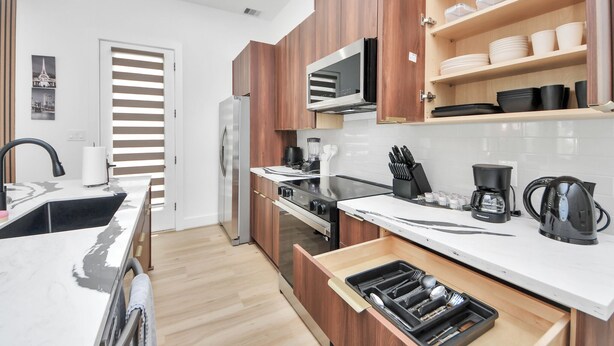 Eine moderne Küche mit Holzschränken, einem Edelstahlkühlschrank, einer Mikrowelle und einer Kaffeemaschine.
