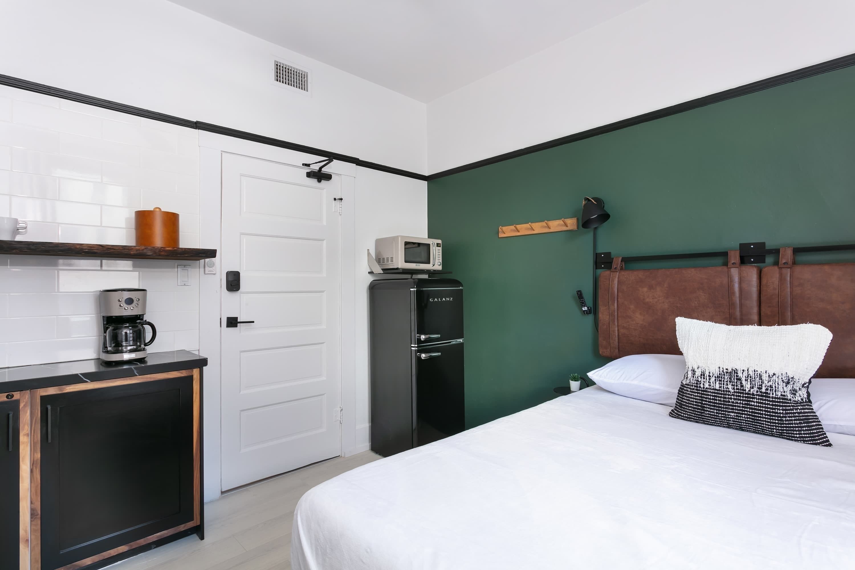 A hotel room with a bed, a coffee machine, a microwave, and a wardrobe.