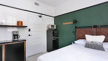 A hotel room with a bed, a coffee machine, a microwave, and a wardrobe.