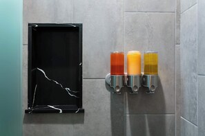 A wall-mounted beverage dispenser with three different colored drinks, a black-framed mirror, and a tiled wall. - La Ventana Hotel - Renovated Room Steps from Gaslamp Quarter (San Diego)