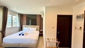 Ein Hotelzimmer mit Bett, Nachttisch, Stuhl, Tür und Fenster.