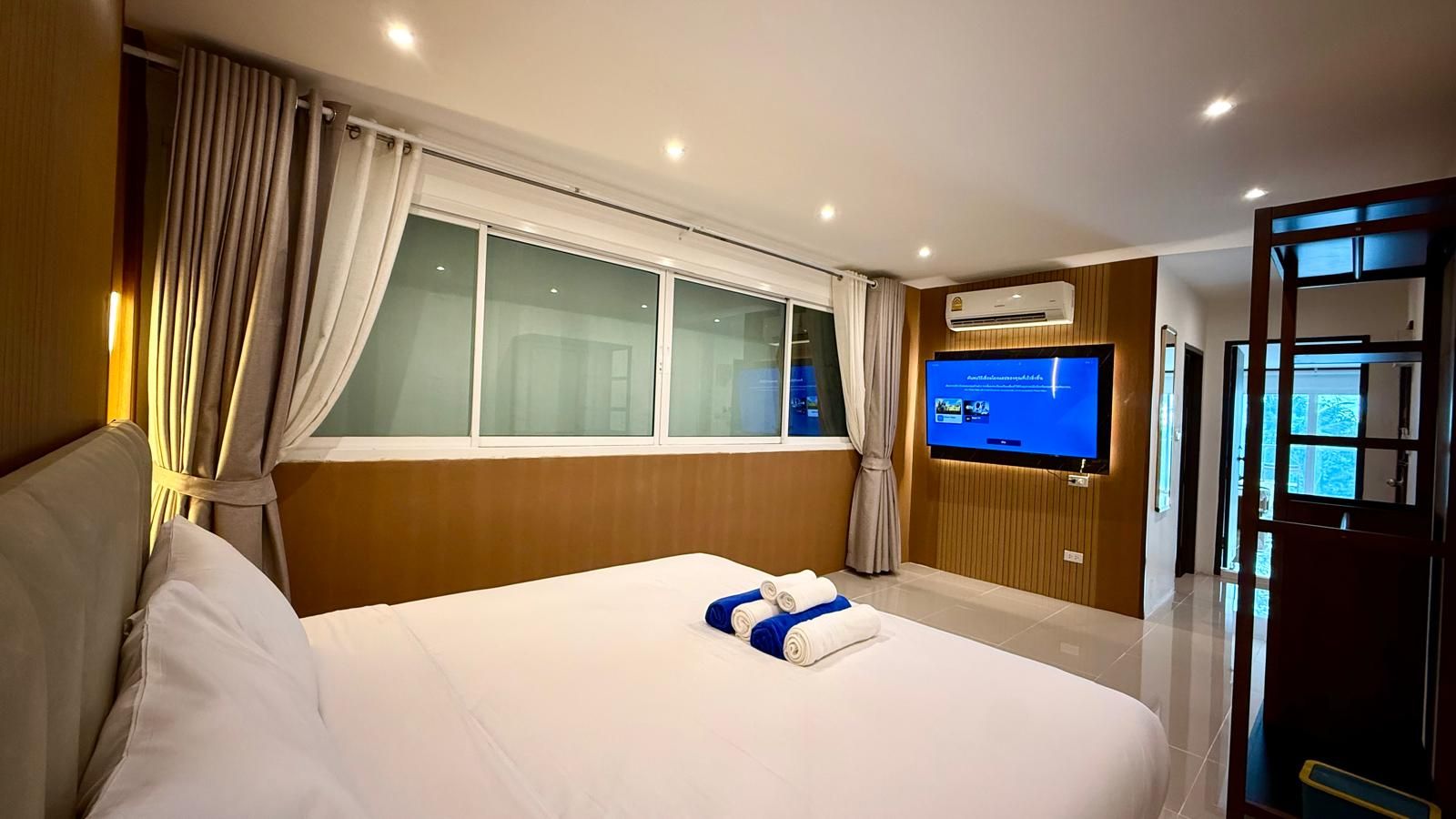 Ein Hotelzimmer mit einem großen Bett, einem Fernseher und einer Klimaanlage.