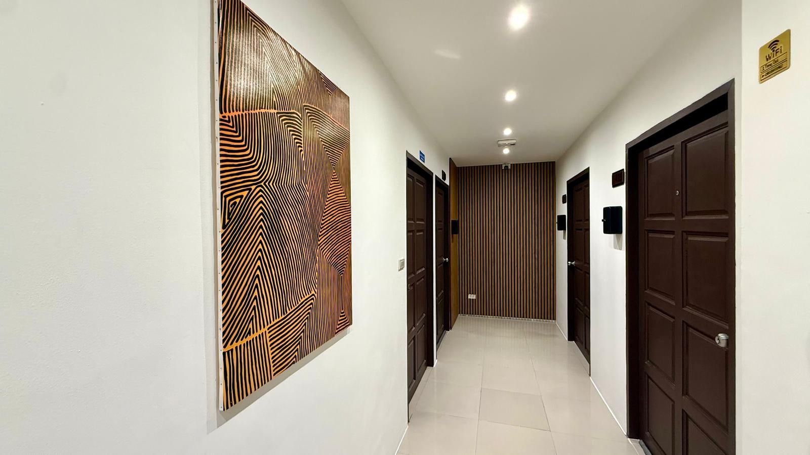 Un pasillo con pared de diseño, puertas de madera y suelo de baldosas.