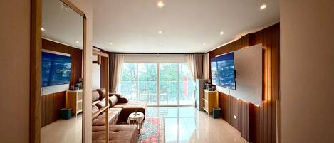 A modern living room with a sofa, a coffee table, and a TV mounted on the wall.