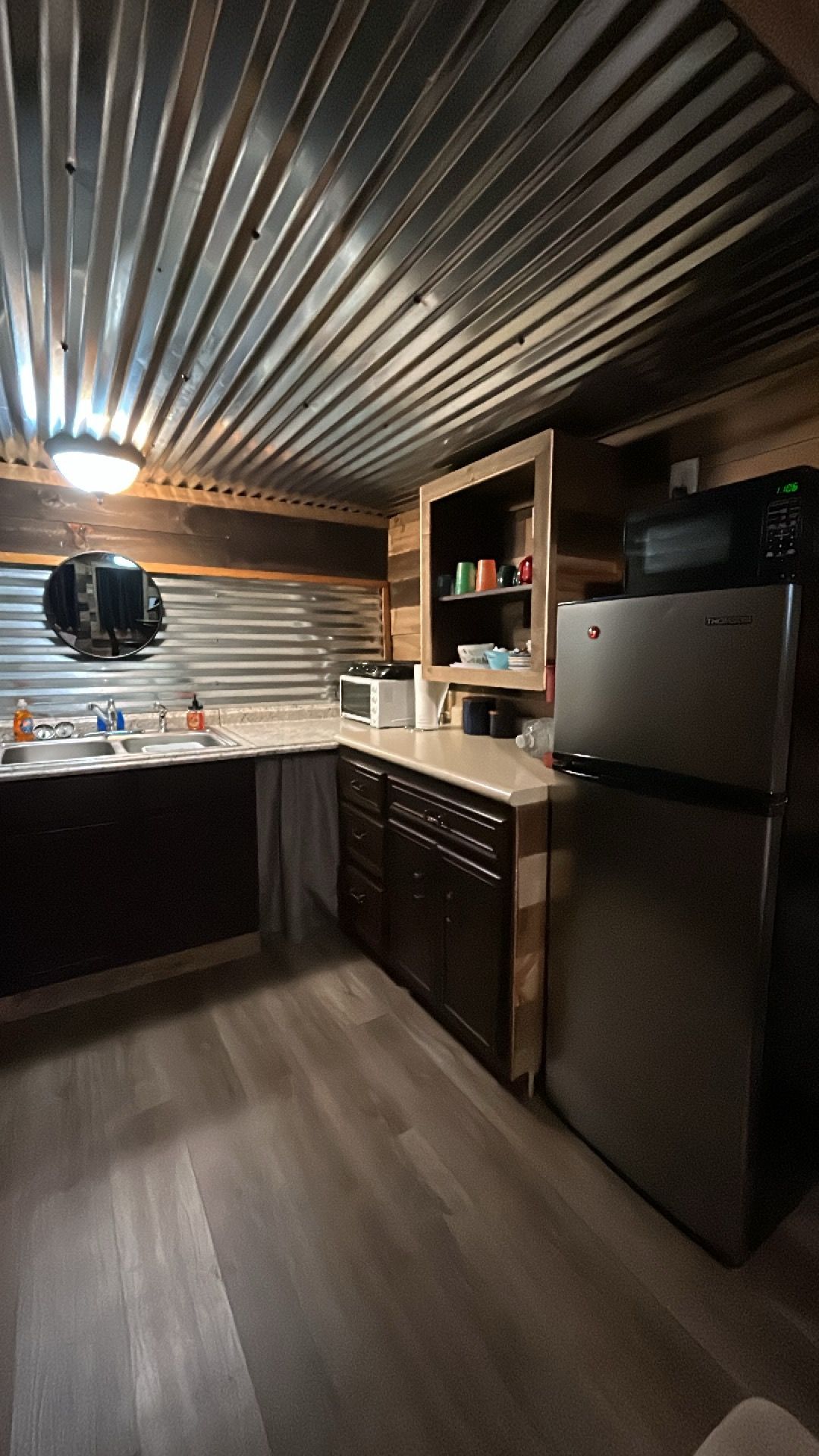 Una cocina con un refrigerador de acero inoxidable, un microondas y un armario de madera.