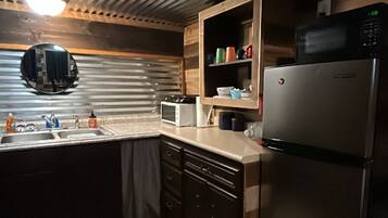 Una cocina con un refrigerador de acero inoxidable, un microondas y un armario de madera.