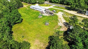 An aerial view of a property with a large building, a fenced area, and a road.