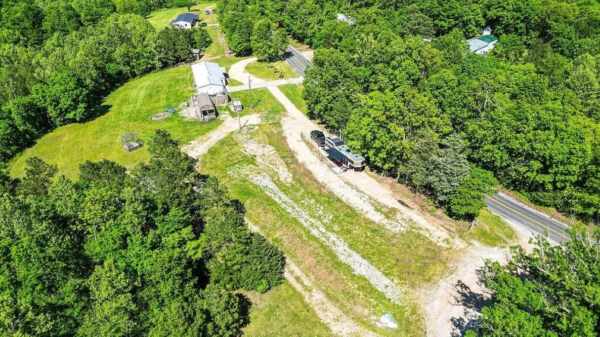 En vy från ovan av en lantlig fastighet med ett stort hus, en uppfart och en parkerad husbil.