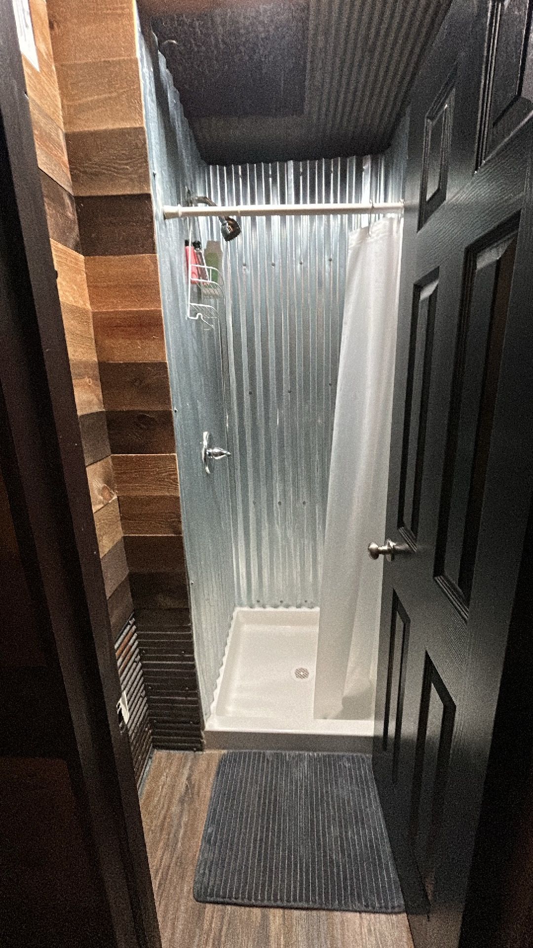 Un baño con ducha, una puerta y un tapete.