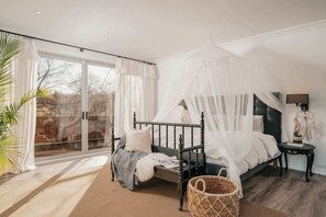 Une chambre à coucher avec un lit à baldaquin, une grande fenêtre et une vue sur l’extérieur.