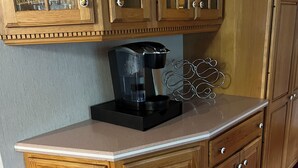 Uma cozinha de madeira com máquina de café embutida, armários e bancada de mármore.