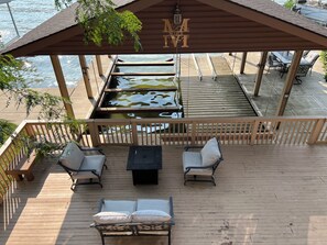 Eine Holzterrasse mit überdachter Sitzgruppe mit Blick auf ein Gewässer.