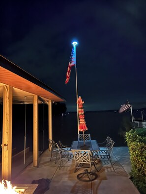 An outdoor patio with a table and chairs, an American flag, and a view of the water. - The "Big Easy" Waterfront Home (Huntsville)