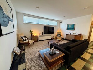 A modern living room with a flat-screen TV, comfortable seating, a coffee table, and a large window with blinds. - Lovely 2-bedroom apartment in Anchorage perfect for your getaway (Anchorage)
